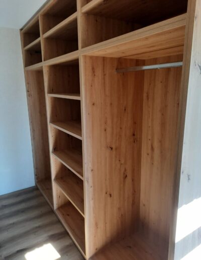 Offener Holzkleiderschrank mit Regalen und Kleiderstange.