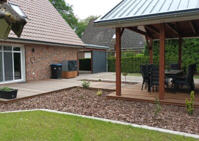 Garten mit Holzterrasse und Gartenhaus.