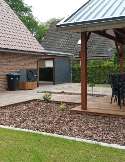 Garten mit Holzterrasse und Gartenhaus.